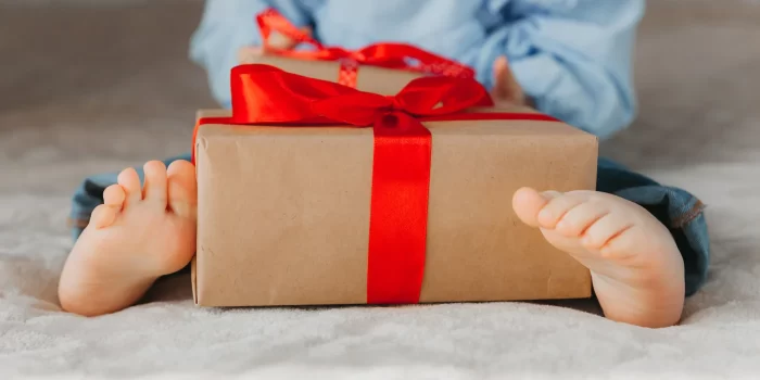 Dovanos kūdikiui – vaiko dovana supakuota į dėžutę su raudonu kaspinu