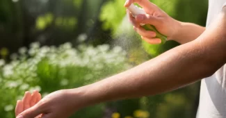 Asmuo purškia natūralų vabzdžių repelentą ant rankos lauke, siekiant apsisaugoti nuo uodų ir kitų vabzdžių