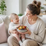Imuniteto stiprinimas mamytėms Mama su kūdikiu laiko šviežius vaisius – simbolizuoja sveiką mitybą imuniteto stiprinimui